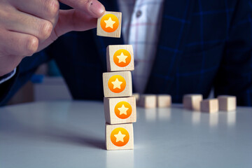 Businessman hand putting yellow star which is printed on wooden cube. Customer evaluation survey...