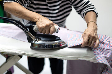 Housewife woman ironing clothes at home Close-up of a woman's hand ironing clothes on an ironing board Cleaning service, maid..