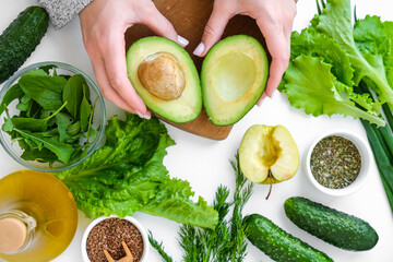 Woman cooking salad of fresh green vegetables and herbs. Raw food concept. Vegan menu. Cooking...
