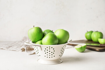 Colander with fresh green apples on table