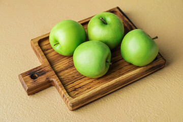 Board with fresh green apples on color background