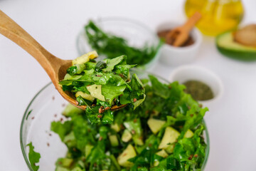 Woman mix salad of fresh green vegetables and herbs. Raw food concept. Vegan menu. Cooking healthy...