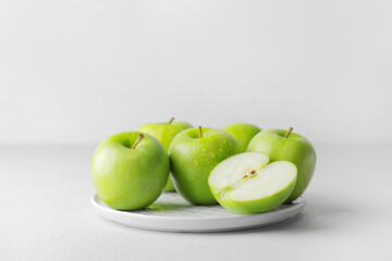 Plate with fresh green apples on white background