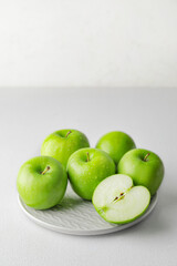 Plate with fresh green apples on white background
