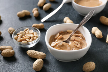 Bowl with tasty peanut butter on dark background