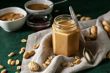 Jar with tasty peanut butter on table