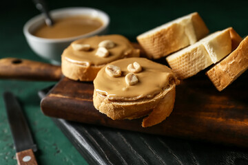 Boards with tasty bread and peanut butter on table, closeup