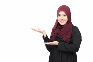 A beautiful Asian Muslim woman is smiling, standing showing and presenting something with hand on white background.