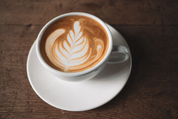 Latte art coffee on wooden table in coffee shop