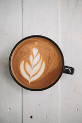 Latte art coffee on wooden table in coffee shop