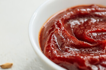 Bowl with tasty barbecue sauce on light background, closeup