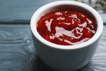 Bowl with tasty barbecue sauce on dark wooden background