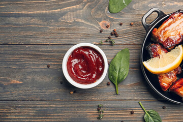 Bowl with tasty barbecue sauce and roasted pork on wooden background