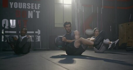 Young muscular athletic group doing training abdomen exercises working out with a medicine ball in fitness gym, strength workout healthy lifestyle sport concept - Powered by Adobe