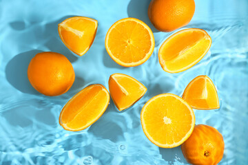 Juicy oranges with water splashes on color background