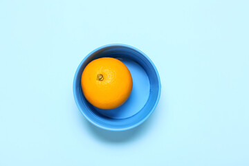 Bowl with fresh juicy orange on color background