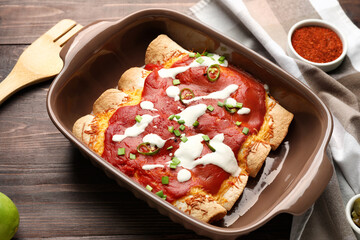 Baking dish with tasty cooked enchilada on table