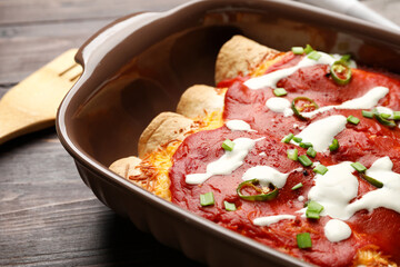Baking dish with tasty cooked enchilada on table, closeup