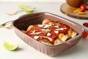 Baking dish with tasty cooked enchilada on table