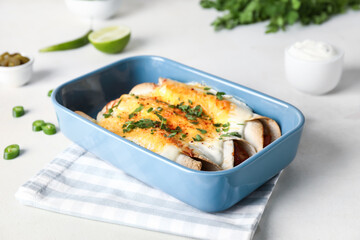 Baking dish with tasty cooked enchilada on table