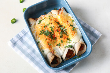 Baking dish with tasty cooked enchilada on white background