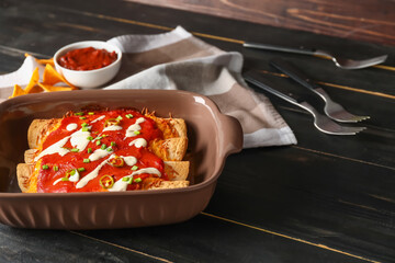 Baking dish with tasty cooked enchilada on table