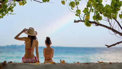 ビーチで虹を眺める母と娘