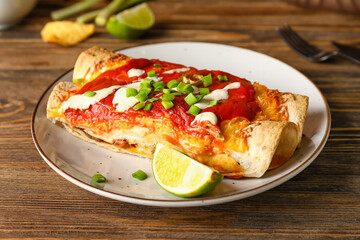 Plate with tasty cooked enchilada on table