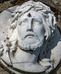 Statue of Jesus Christ with his eyes turned to his forehead where a fly sits.