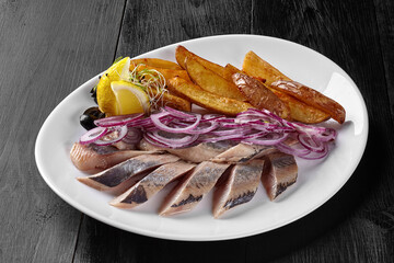 Salted herring with fried potato wedges, onion and lemon