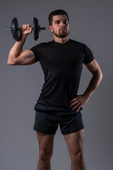 Sporty young man doing dumbbell one arm shoulder press