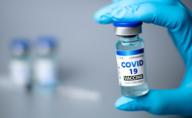 Obraz premium doctor wearing blue gloves Showing bottle of vaccine for testing COVID-19 on white background. Corona virus protection concept and influenza immunity.