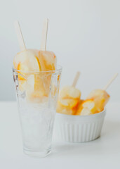 Summer cold drinks, citrus fruit cocktail - orange and lemon, with ice, and popsicles on a stick.