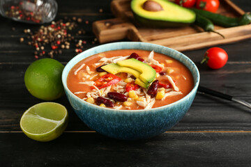Bowl of tasty chicken enchilada soup on table
