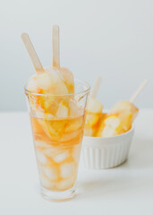 Summer cold drinks, citrus fruit cocktail - orange and lemon, with ice, and popsicles on a stick.