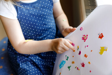 Little toddler girl playing with different colorful animal stickers. Concept of activity of...