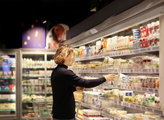 Young man shopping in supermarket, reading product information.
