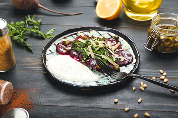 Plate with delicious beetroot carpaccio on dark wooden background