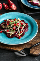 Plate with delicious beetroot carpaccio on dark wooden table