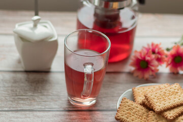 Morning tea is on the table. Flowers and biscuits lie nearby.