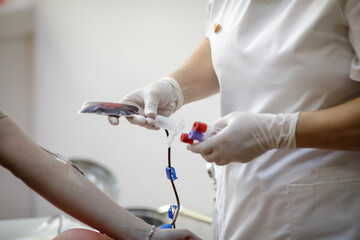 Shallow depth of field (selective focus) details with the hands of a medical worker preparing a volunteer for donating blood.