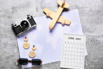 Calendar, world map and travel accessories on grunge background