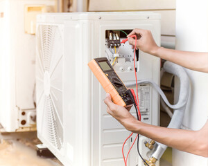 Air conditioner repairman using electricity meter to check air conditioner operation, maintenance...