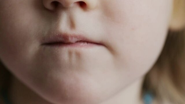A little girl eats a vitamin in the form of a bear. The concept of strengthening children's health with multivitamin complexes. Close-up