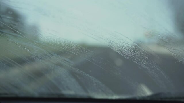 Broken window wipers removing water drops from dirty windshield of car. Concept driving safety and visibility during trip.