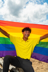 Young gay man proudly holding the lgbt flag in his hands