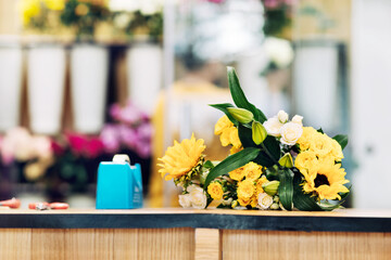 A beautiful bouquet of bright mixed flowers lies on a wooden table, the work of a florist in a flower shop.