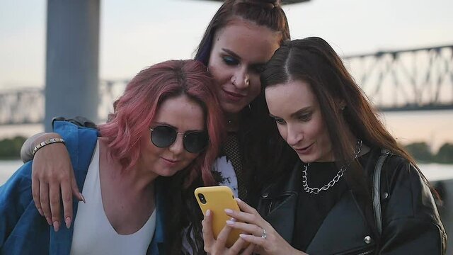 Happy group of friends watching funny content on smartphone display outdoors
