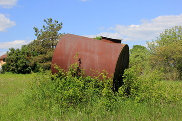 Obraz premium Large metal barrel for water. A metal water barrel stands in the garden.Old rusty Barrel for Irrigation at the Agricultural Field 