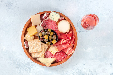 Charcuterie and cheese board, shot from above with a glass of rose wine. Prosciutto di Parma ham, blue cheese, olives and crackers, gourmet antipasti